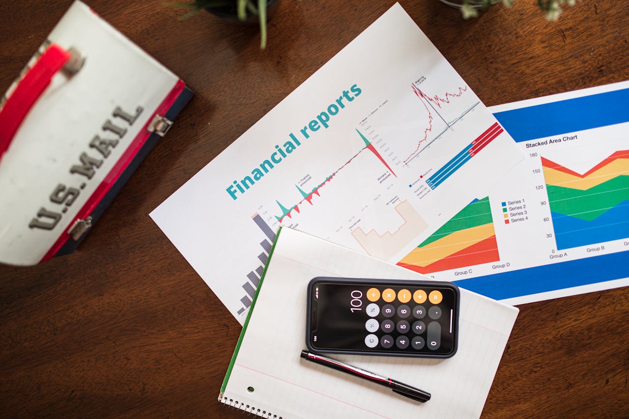 Overhead view of financial reports, charts, and a calculator on a desk.